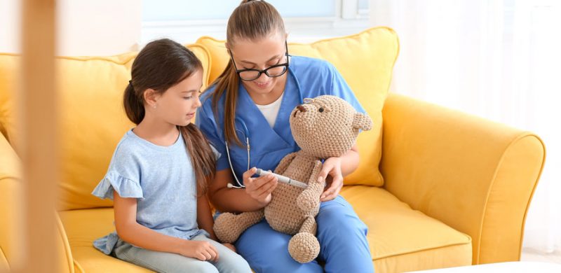 Une médecin montrant à une petite fille diabétique avec un nounours comment s'injecter de l'insuline.