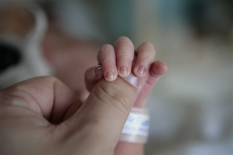 Pouce d'un adulte dans le creux de la main d'un nourrisson