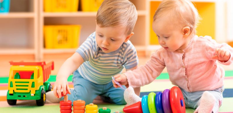 Deux bébés jouant ensemble dans une crèche avec des jeux en bois